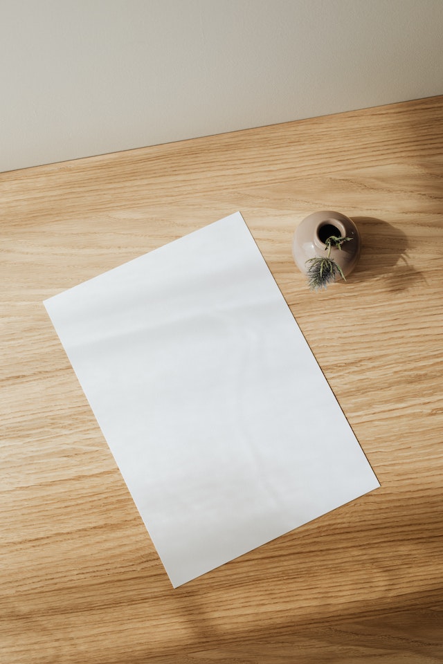 A blank sheet of paper on a wooden desk hinting at writer's block